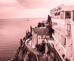 a building on a cliff next to the water at Hotel Voce del Mare in Vietri sul Mare