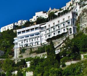 Hotel Voce del Mare في فيتري: مبنى ابيض على جانب جبل