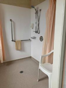 a bathroom with a white chair and a shower at Waiouru Welcome Inn in Waiouru