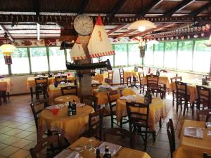 a restaurant with tables and chairs and a clock at Campeggio Al Bosco in Grado