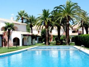 a swimming pool in front of a house with palm trees at Cabañas 59 in Denia