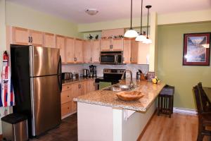 una cocina con nevera de acero inoxidable y armarios de madera en Renovated Condo, 2BR, 2BA, Heated Pool, 3 Hot Tubs, Pets Welcome! en Canmore