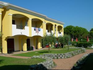 un gran edificio amarillo con una pared de piedra delante de él en Villaggio Borgo dell'Ulivo, en Bibione