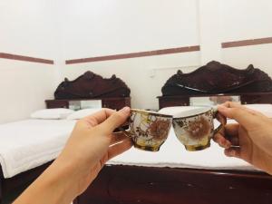 ヴィンロンにあるThien Thanh Hotelのカップをベッドの前に置く者
