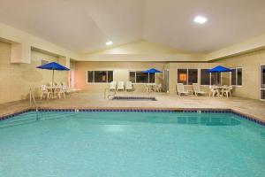 una piscina con sombrillas azules, mesas y sillas en Days Inn by Wyndham Fremont, en Fremont