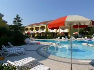 a swimming pool with white chairs and an umbrella at Villaggio Borgo dell'Ulivo in Bibione