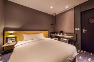 una camera da letto con un grande letto bianco e una scrivania di Walker-Taoyuan a Taoyuan