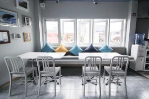 een keuken met 2 tafels, stoelen en ramen bij The Moon Hostel Huahin in Hua Hin