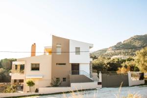 biały dom z wzgórzem w tle w obiekcie Our House Luxury Suites w mieście Palaión Tsiflíkion