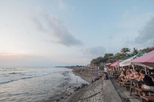 a crowd of people sitting on a beach at Caroline Guest House in Canggu