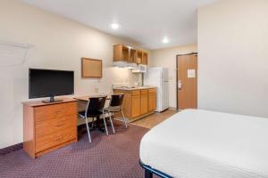 a hotel room with a bed and a desk with a television at Suburban Studios Huntsville University Area in Huntsville