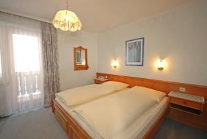 una camera da letto con un letto grande e un lampadario di Pension Riedlsperger a Saalbach Hinterglemm