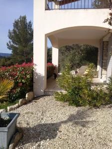 a white house with a dog sitting under a patio at Le Logis in Gordes