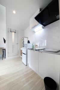 a white kitchen with white appliances and a wooden floor at Culinary Bed&Art 402 in Hamamatsu