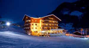 a large building in the snow at night at Hotel Roslehen in Grossarl