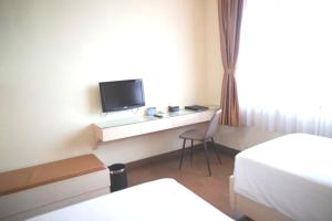 a bedroom with a desk with a tv and a chair at Anugrah Hotel Sukabumi in Sukabumi