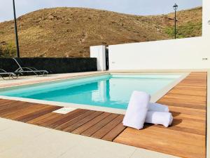 a swimming pool with a chair sitting on a wooden deck at Canaryislandshost l Infinity Views in Nazaret