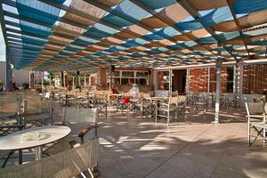 a patio with tables and chairs under a blue ceiling at ILIOS K Village Resort in Tigaki
