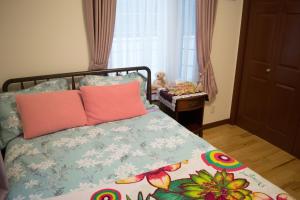 Un dormitorio con una cama con almohadas rosas. en La Fata en Uruma