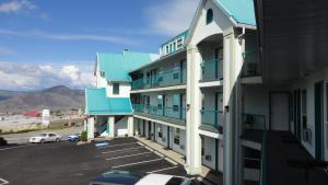 a building with blue balconies and a parking lot at Alpine Motel in Kamloops