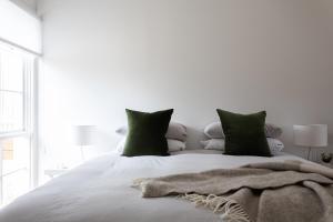 a white bed with green pillows and a blanket on it at A Cottage In Richmond in Richmond +13 photos