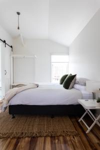 a white bedroom with a large bed and a table at A Cottage In Richmond in Richmond
