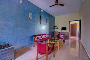 uma sala de jantar com cadeiras vermelhas e uma parede azul em Holidayincoorg Cozy Nest em Madikeri