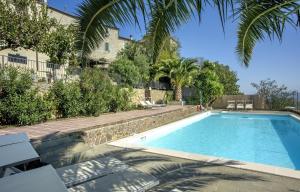 a swimming pool with palm trees and a building at Hotel Vatluna in Vetulonia