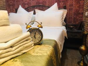 uma cama com almofadas brancas e um relógio num banco em Marani Boutique Hotel em Tbilisi