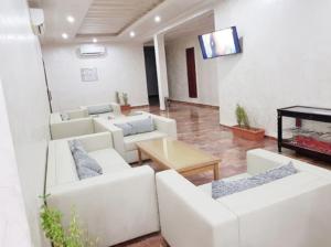 a living room with white furniture and a flat screen tv at TAKIALT in Adrar