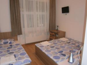 a bedroom with two beds and a table and a television at Fanni Budapest Guesthouse in Budapest