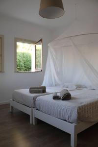 Una cama blanca con dosel en un dormitorio en Cabanas Jardim & Ria en Cabanas de Tavira