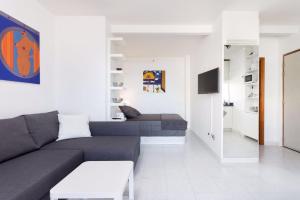 ein Wohnzimmer mit einem grauen Sofa und einem TV in der Unterkunft Perla's House Studio with incredible sea view in Puerto de la Cruz