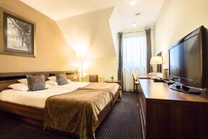 ミエレツにあるRado Resort Spa & Wellnessのベッド1台、薄型テレビが備わるホテルルームです。
