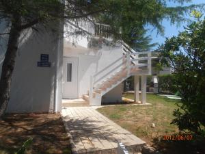une maison blanche avec un escalier dans une cour dans l'établissement Apartments Febsis, à Novalja
