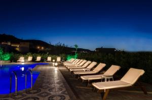 Eine Reihe von Liegestühlen neben einem Pool bei Nacht in der Unterkunft Ilios Stalis in Stalida