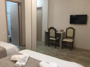 Cette chambre comprend deux chaises, un bureau et une télévision. dans l'établissement Family Hotel Triston, à Tbilissi