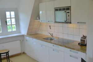 uma cozinha branca com um lavatório e um micro-ondas em Schlottmann em Keitum