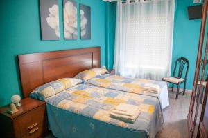 Un dormitorio con una cama con paredes azules y una ventana en Pensión Parque del Ebro en Logroño