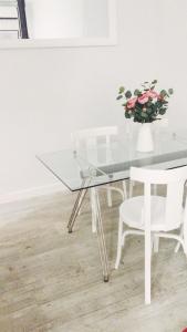 a glass table with a white chair and a vase with flowers at Reina Victoria 46 in Madrid