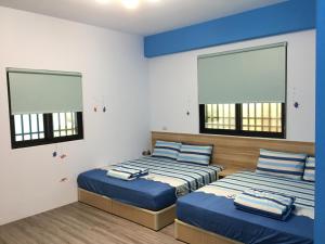 two beds in a room with two windows at Meow Meow Fish B&B in Baisha