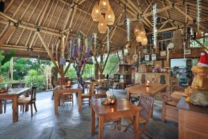 un restaurant avec des tables, des chaises et des lustres en bois dans l'établissement Gusde Tranquil Villas by EPS, à Ubud