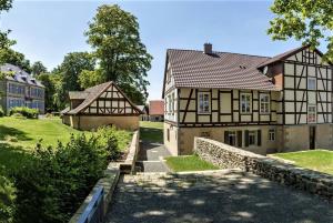 ein altes Gebäude mit einer Steinmauer neben einem Haus in der Unterkunft Gutshof Schäferhaus in Frielendorf