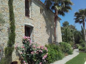 a brick building with flowers and a palm tree at La Bastide de l'Oliveraie in Le Castellet