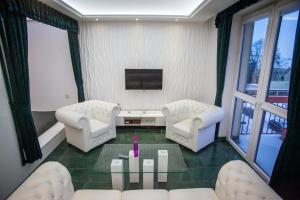 sala de estar con 2 sillas blancas y mesa en Royal Apartment in City Centre, en Suwałki