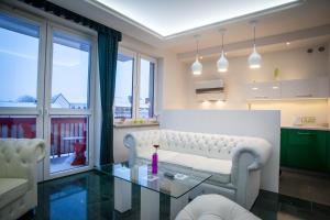 a living room with a white couch and a glass table at Royal Apartment in City Centre in Suwałki