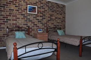 a bedroom with two beds and a brick wall at Rainbow Cottage in Rainbow Beach