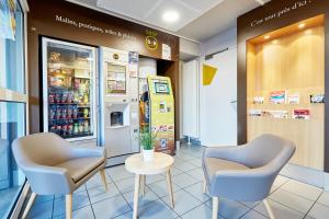 a store with two chairs and a vending machine at B&B HOTEL CAEN Sud in Ifs