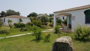 a garden in front of a white house at Hotel Baia Cea in Bari Sardo