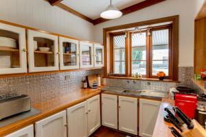 eine Küche mit weißen Schränken, einem Waschbecken und Fenstern in der Unterkunft Grand Cru Estate Homestead in Springton